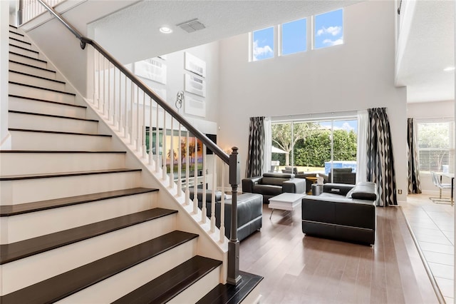 staircase featuring hardwood / wood-style flooring, a textured ceiling, and a high ceiling