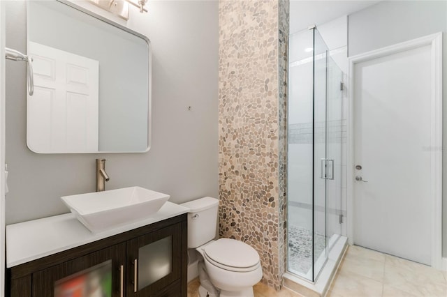 bathroom with tile patterned flooring, toilet, vanity, and a shower with shower door