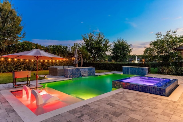 pool at dusk featuring pool water feature, an in ground hot tub, and a patio