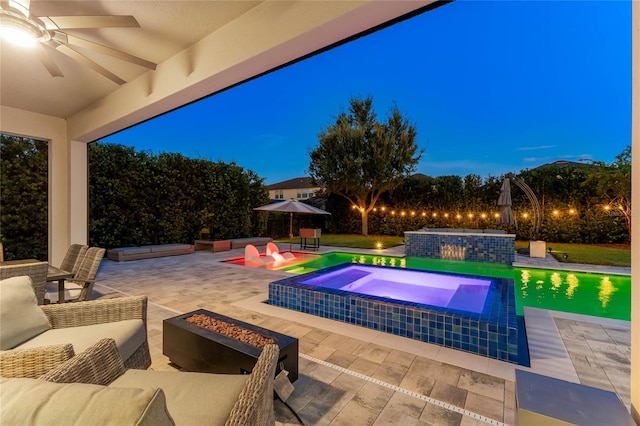 pool at night with a patio area, an outdoor hangout area, an in ground hot tub, and ceiling fan