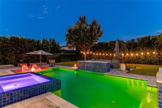 pool at twilight with an in ground hot tub and a patio