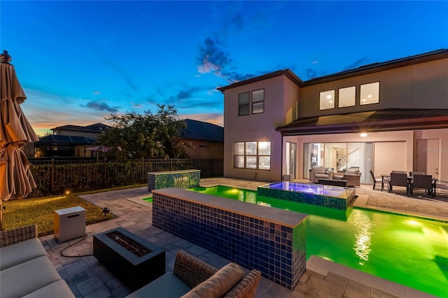 patio terrace at dusk with an outdoor living space with a fire pit and a swimming pool with hot tub