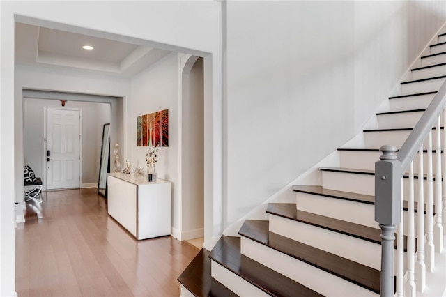 stairway with a raised ceiling and hardwood / wood-style flooring