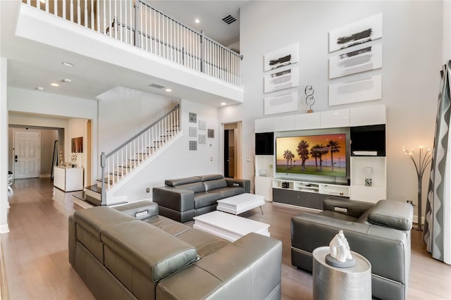 living room with a towering ceiling and wood-type flooring