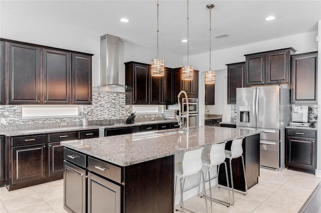 kitchen featuring a center island, decorative light fixtures, wall chimney exhaust hood, tasteful backsplash, and stainless steel fridge with ice dispenser