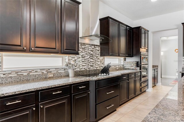 kitchen featuring wall chimney exhaust hood, stone countertops, light tile patterned floors, black electric stovetop, and backsplash