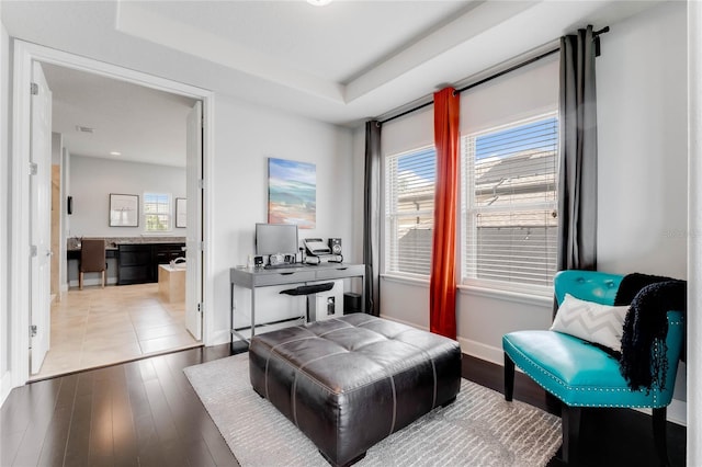 sitting room with hardwood / wood-style flooring, a raised ceiling, and a wealth of natural light