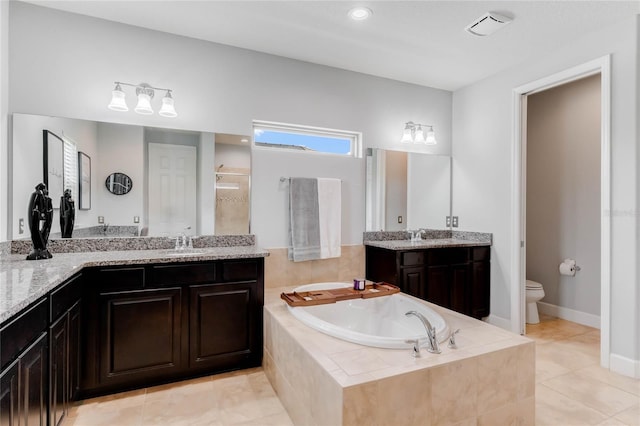 bathroom with tile patterned floors, double vanity, a relaxing tiled tub, and toilet