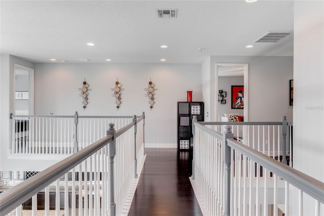 hallway with a textured ceiling and dark hardwood / wood-style flooring