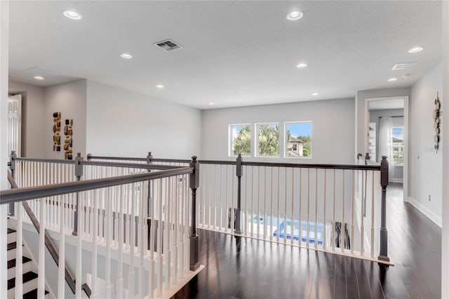 hall with a textured ceiling and dark hardwood / wood-style flooring