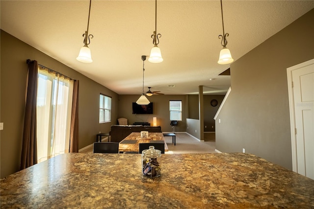 kitchen with carpet floors, dark stone countertops, decorative light fixtures, and baseboards