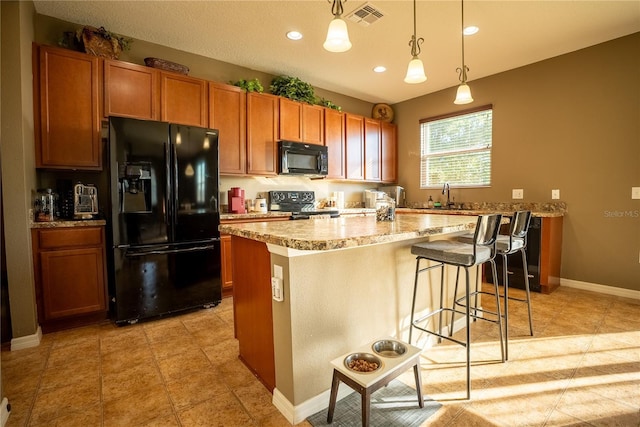 kitchen featuring a sink, visible vents, a center island, black appliances, and brown cabinetry