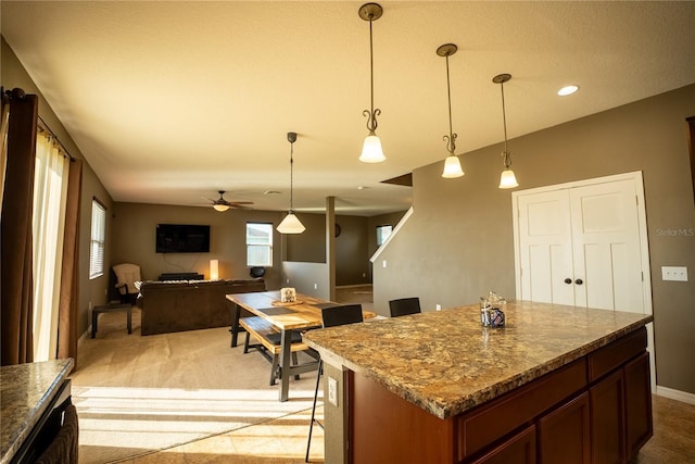 kitchen featuring baseboards, a kitchen bar, a kitchen island, and pendant lighting