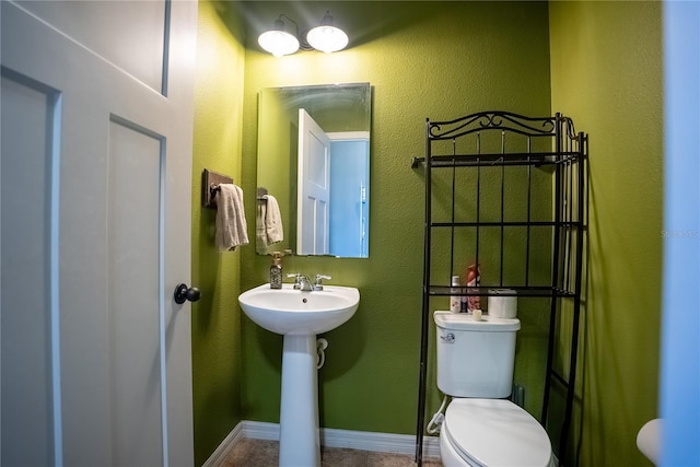 bathroom featuring toilet, baseboards, and a sink