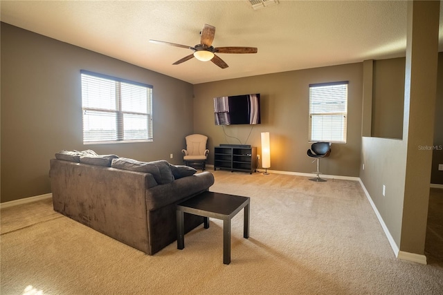 living room with light carpet, plenty of natural light, baseboards, and a ceiling fan