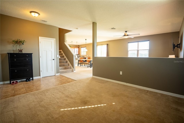 tiled empty room featuring carpet floors, visible vents, stairway, and a textured ceiling