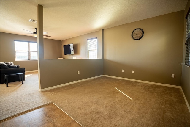 interior space featuring visible vents, ceiling fan, a textured ceiling, and baseboards