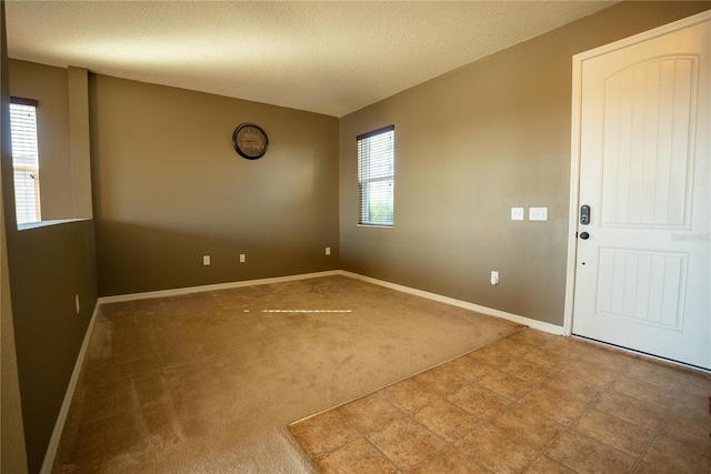 spare room featuring a textured ceiling, carpet floors, and baseboards