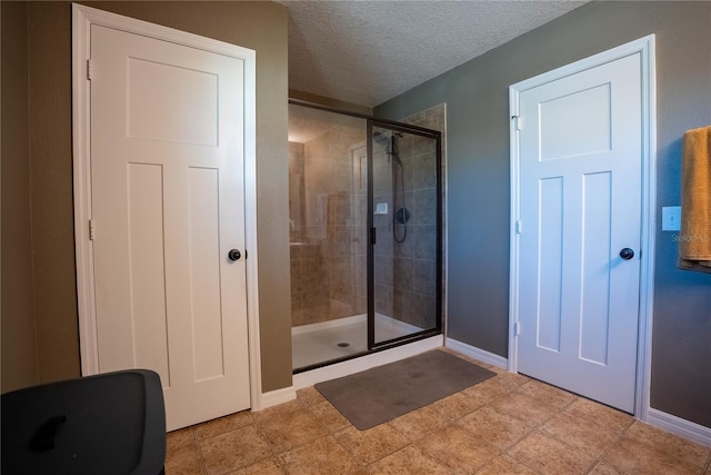 full bathroom with a shower stall, baseboards, and a textured ceiling