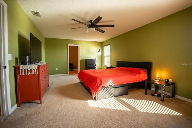 bedroom with a textured ceiling, light colored carpet, a ceiling fan, visible vents, and baseboards