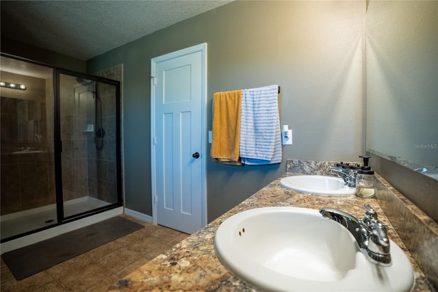 bathroom featuring a stall shower, tile patterned flooring, a textured ceiling, and a sink