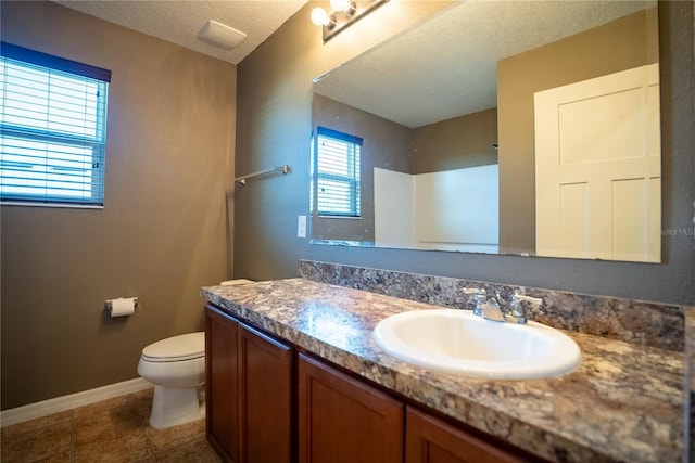 bathroom featuring toilet, vanity, a textured ceiling, tile patterned flooring, and baseboards