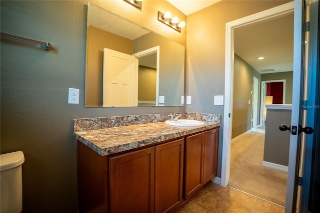 bathroom with tile patterned flooring, baseboards, vanity, and toilet