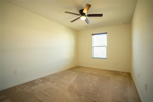 empty room featuring baseboards, a textured ceiling, a ceiling fan, and light colored carpet