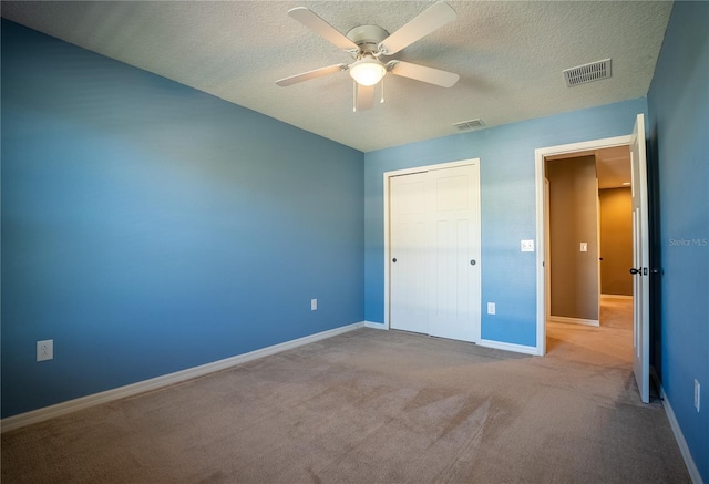 unfurnished bedroom with baseboards, visible vents, a textured ceiling, and carpet flooring