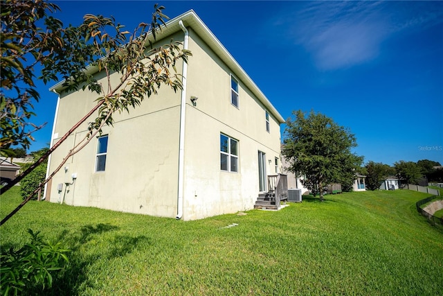 view of property exterior featuring central AC, a lawn, and stucco siding