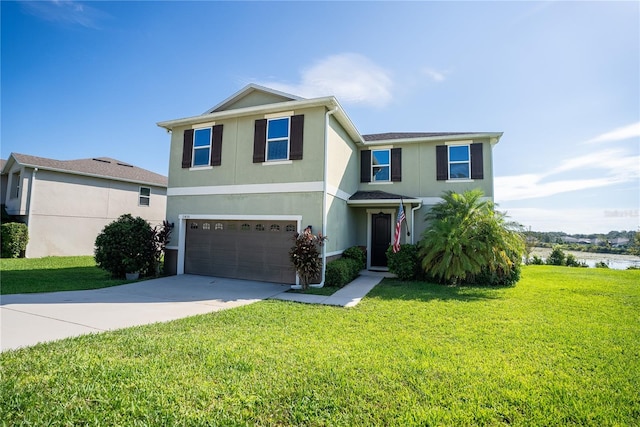 traditional-style house with stucco siding, a water view, a front yard, a garage, and driveway