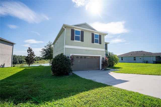 view of front of home with an attached garage, driveway, a front yard, and stucco siding