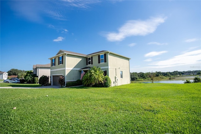 view of side of property featuring an attached garage, a water view, a yard, concrete driveway, and stucco siding