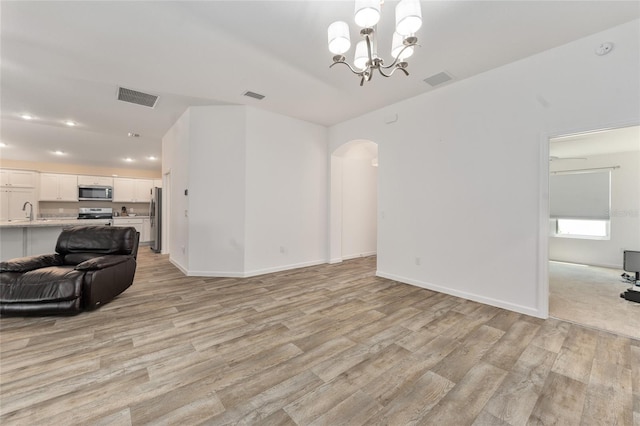 living room featuring light wood-type flooring, sink, and a notable chandelier