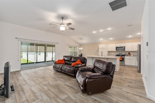 living room featuring vaulted ceiling, ceiling fan, and light hardwood / wood-style flooring