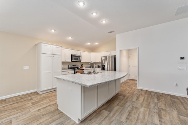 kitchen featuring sink, appliances with stainless steel finishes, white cabinets, and an island with sink