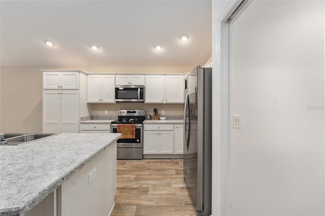 kitchen with light wood-type flooring, sink, white cabinets, and stainless steel appliances