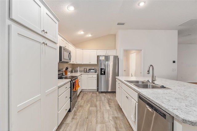 kitchen featuring white cabinetry, lofted ceiling, light hardwood / wood-style floors, sink, and appliances with stainless steel finishes