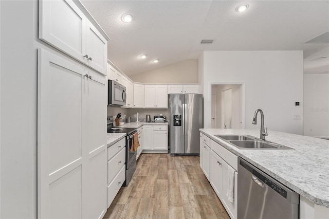 kitchen featuring appliances with stainless steel finishes, lofted ceiling, light hardwood / wood-style floors, sink, and white cabinetry