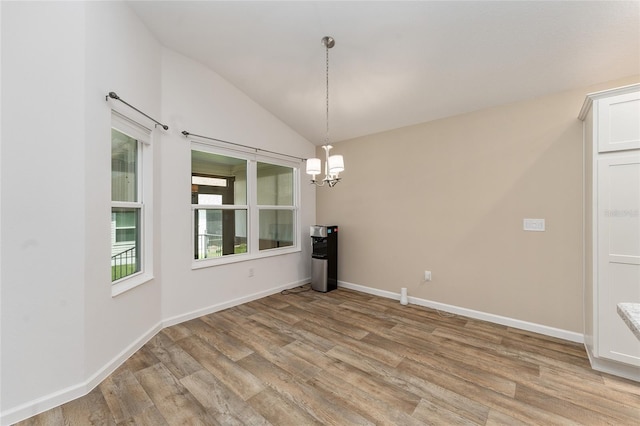 unfurnished dining area featuring lofted ceiling, a notable chandelier, and light hardwood / wood-style floors