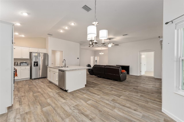 kitchen featuring an island with sink, stainless steel appliances, decorative light fixtures, sink, and white cabinets