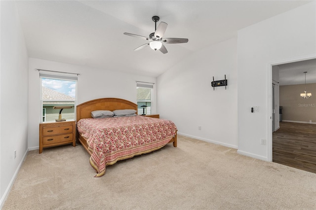 carpeted bedroom featuring ceiling fan with notable chandelier, vaulted ceiling, and multiple windows