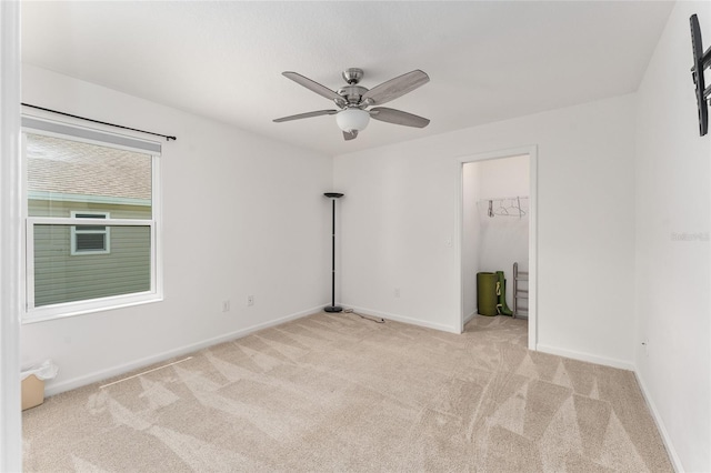 unfurnished bedroom with a closet, ceiling fan, a spacious closet, and light colored carpet