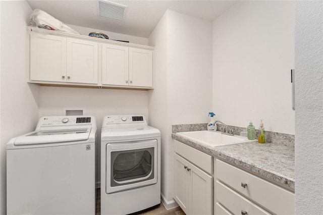 clothes washing area with sink, cabinets, and separate washer and dryer