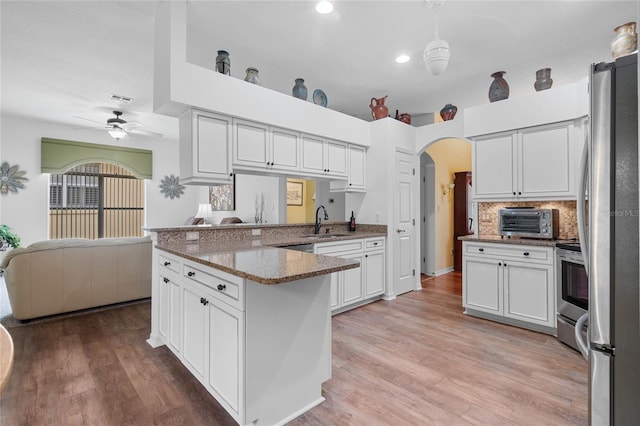 kitchen with backsplash, sink, light wood-type flooring, appliances with stainless steel finishes, and ceiling fan