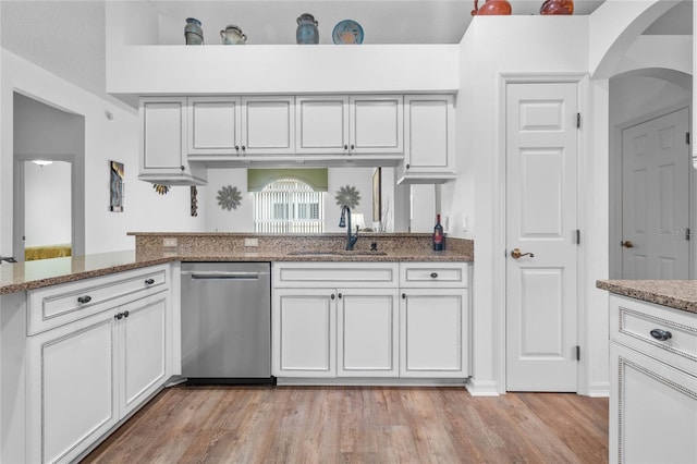 kitchen featuring light stone counters, light wood-style flooring, white cabinetry, a sink, and dishwasher