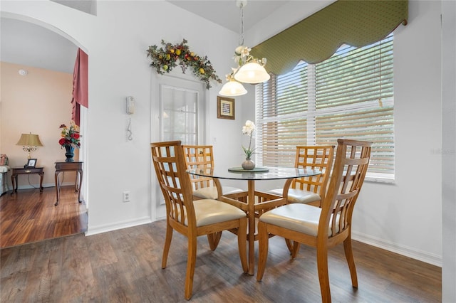 dining room featuring baseboards, arched walkways, and wood finished floors