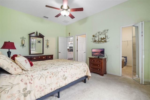 bedroom with a spacious closet, a closet, ceiling fan, and light carpet