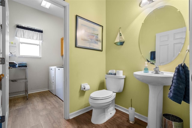 bathroom with hardwood / wood-style floors, washing machine and dryer, and toilet