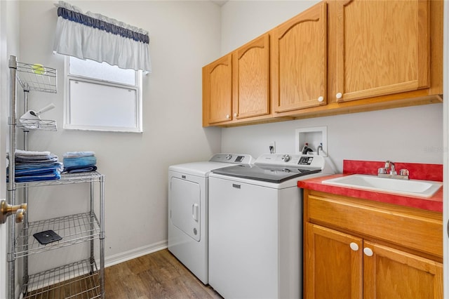 clothes washing area featuring washer and dryer, sink, dark wood-type flooring, and cabinets